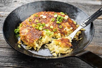 Traditionelles schweizer Rösti als Beilage als closeup in einer geschmiedeten Eisenpfanne 