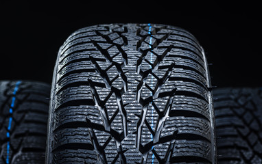 Set of new winter tires on black background with contrasty lighting. Close up product photograph of unused tyres