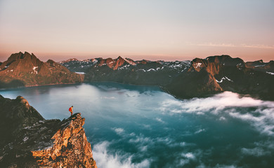 Norway travel man tourist alone on the edge cliff mountains above fjord hiking adventure lifestyle...