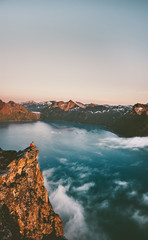 Man sitting on the edge cliff mountains above sea traveling alone adventure lifestyle weekend in Norway solitude emotions