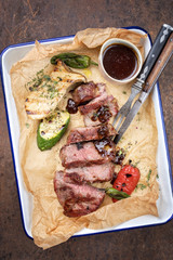 Traditional German barbecue sliced rostbraten with fried mushrooms and paprika as top view on backing paper in a skillet