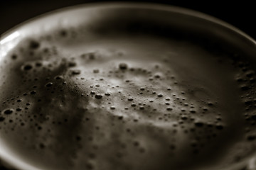 Stylish image of coffee with foam in muted tones colored into bronze in a dark aura