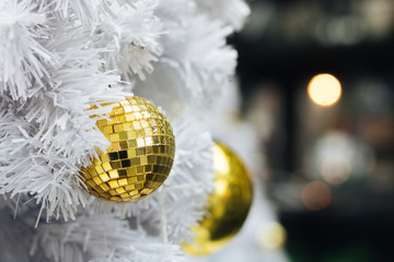 Golden christmas ball on white christmas tree