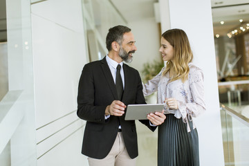 Young businesswoman and businessman look on digital tablet and discuss aout project
