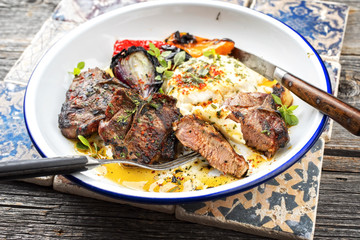 Barbecue t-bone lamb steak with carbonized onion and chili as top view in a white plate