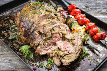 Traditional leg of lamb sliced with vegetable skewer as closeup on a metal sheet
