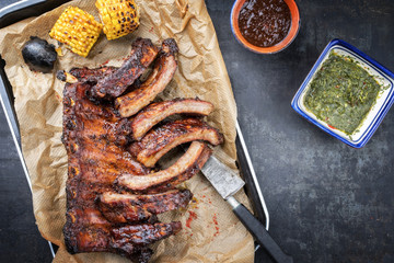 Barbecue spare ribs St Louis cut with hot honey chili marinade and chimichurri sauce as top view in a skillet