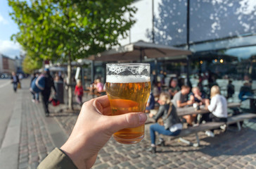 Beer in hand of visitor of street food market of Copenhagen, Denmark. Leisure in Scandinavia with...