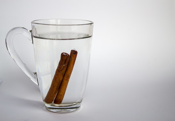 Cinnamon tea in glass cup on white background
