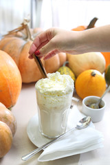 Deser kawowy. Smakowita kawa z mlekiem i bitą śmietaną na tle jesiennych dyń.