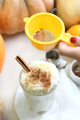 Kawa z cynamonem. Smakowita kawa z mlekiem i bitą śmietaną na tle jesiennych dyń.