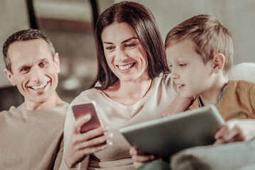 Joyful mood. Charming brunette expressing positivity while demonstrating her telephone