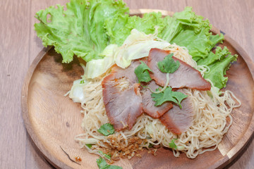 egg noodle soup with red roasted pork on wooden plate