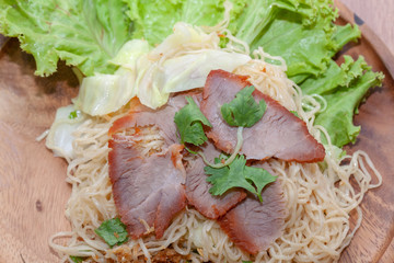 egg noodle soup with red roasted pork on wooden plate