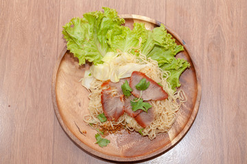 egg noodle soup with red roasted pork on wooden plate