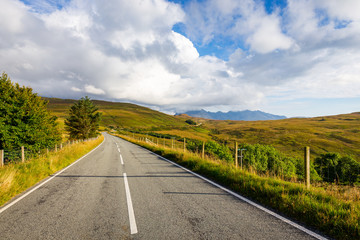 Empty curved road on Isle of Skye leading towards Black Cuillin Mountain ridge in the distance, Scotland