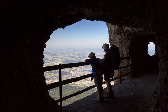 Hikers inside a rocky gallery on the Pilatus mountainn area, in the background the city and the lake of Lucerne, Border Area between the Cantons of Lucerne, Nidwalden and Obwalden, Switzerland, Europe