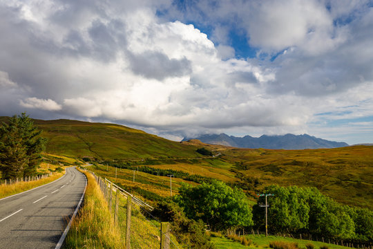 Empty Curved Road On Isle Of Skye Leading Towards Black Cuillin Mountain Ridge In The Distance, Scotland