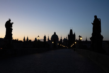 Blick am frühen Morgen über die Statuen der menschenleeren Karlsbrücke in Prag Richtung Altstädter Brückenturm