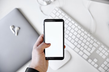 Left hand holding a mobile phone over the desk