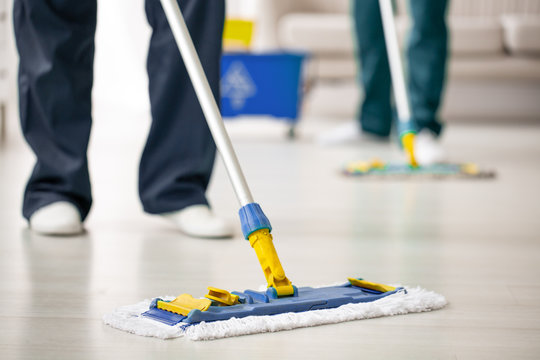 Close-up on mop on the floor holding by cleaning expert while purifying interior