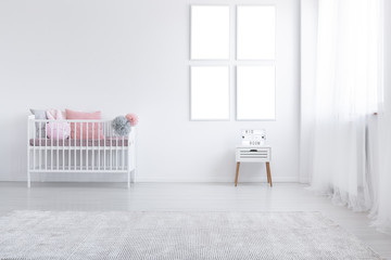Mockup of empty posters above cabinet in white kid's room interior with cradle and carpet. Real...