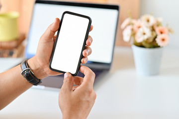 Male hands holding mobile phone in office.