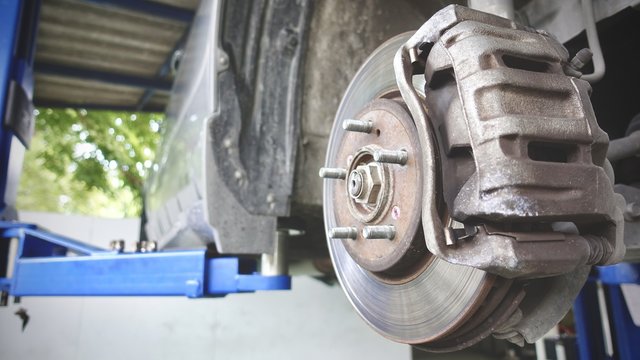 corrugation vehicle's exhaust system at shallow depth of field and Disc brake of the vehicle for repair, in process of new tire replacement. Car brake repairing in garage.Close up.