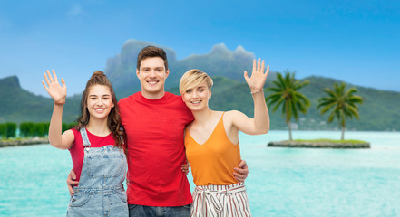 travel, tourism and summer holidays concept - group of happy smiling friends hugging at touristic resort over bora bora island beach background - obrazy, fototapety, plakaty