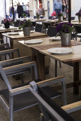 tables decorated with vases on the terrace of an elegant restaurant on the street of a city
