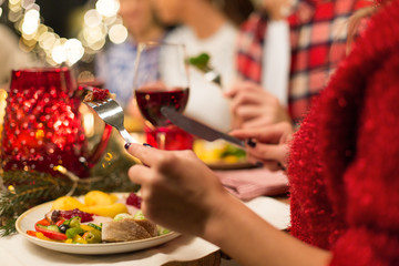 holidays, food and celebration concept - close up of friends having christmas dinner and eating