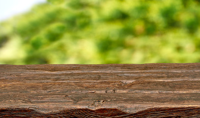 Empty wooden table edge outdoor with blurry green background