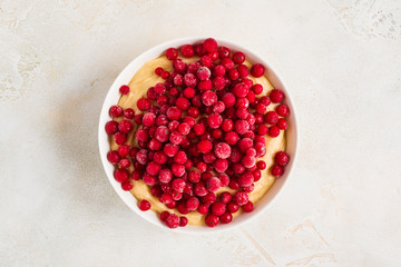 Cranberries adding to a sweet dough for muffins, white bowl, top view