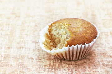 Close up single banana cup cake bakery was bited, look delicious on wooden table background, vintage tone.