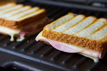 Preparing tasty toast with ham and cheese on grill