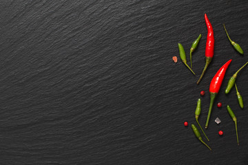Panele Szklane  Jedzenie pikantne tło prezentacji czerwone chili i zielone chili na czarnej tablicy łupkowej