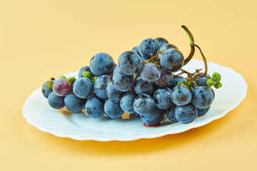 Red wine grape on white plate isolated