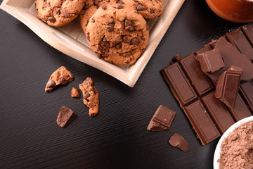 Biscuits and chocolate on black table top view composition