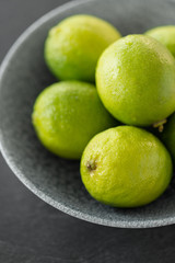 food, healthy eating and vegetarian concept - close up of whole limes in bowl
