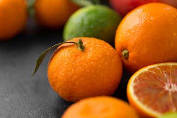 food, healthy eating and vegetarian concept - close up of citrus fruits on stone table
