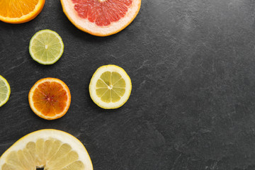 Fototapeta na wymiar food and healthy eating concept - close up of grapefruit, orange, pomelo, lemon and lime slices on stone background