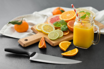 food , healthy eating and vegetarian concept - mason jar glass with juice and citrus fruits on slate table top