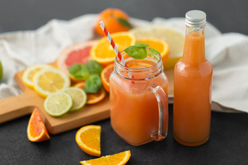 food , healthy eating and vegetarian concept - mason jar glass and bottle of orange or grapefruit...