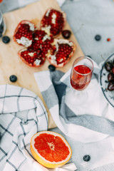 Summer picnic in nature, beautiful fruits and wine. Pomegranate, apples, pastries and bread on a blanket. Cheese and cherries in a beautiful design on the table