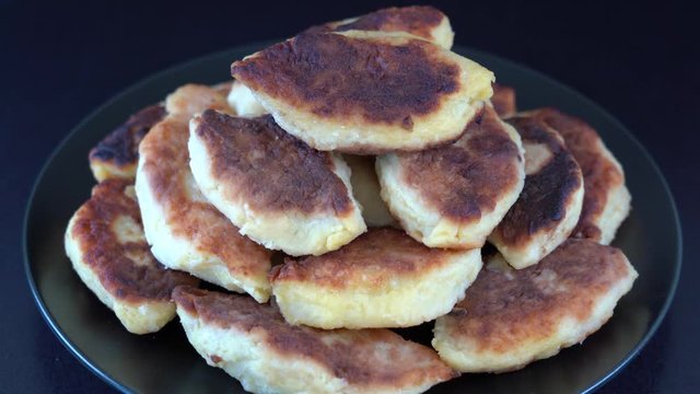 Potato cakes, ukrainian name potato zrazy, stuffed mushrooms or meat or cheese with herbs cream are fried in vegetable oil on black background, close up, rotates. Traditional Ukrainian cuisine