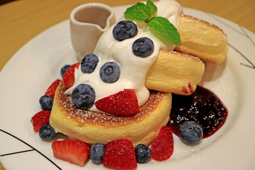 Fluffy Souffle Pancake with Fresh Mix Berries and Mascarpone Cream Served on white Plate 
