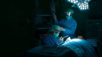 Several surgeons surrounding patient on operation table during their work.Medical team performing...