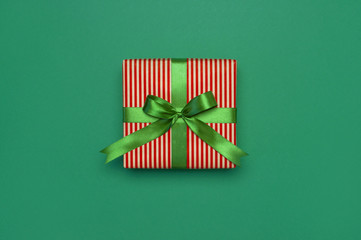 Gift box with green ribbon on green background top view flat lay. Holiday concept, birthday gift,...