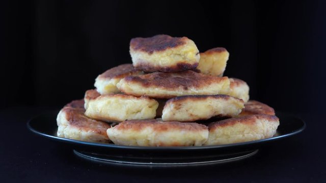 Potato cakes, ukrainian name potato zrazy, stuffed mushrooms or meat or cheese with herbs cream are fried in vegetable oil on black background, close up, rotates. Traditional Ukrainian cuisine