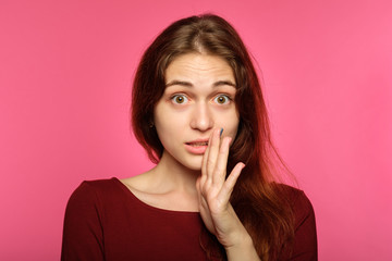 surprised astonished overwhelmed girl. young beautiful woman with brown hair on pink background. emotional facial expression and reaction concept.